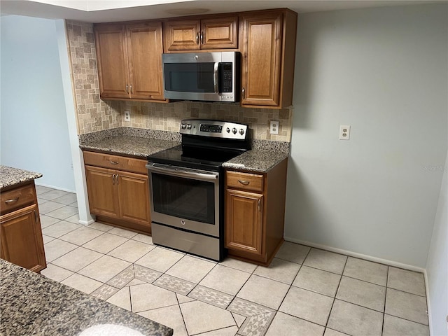 647 Fairmont Ave Unit C, Safety Harbor, FL 34695 - kitchen featuring stainless steel appliances, backsplash, light tile patterned floors, and brown cabinets