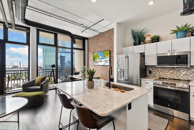 175 S 2nd St S Ph-16, Saint Petersburg, FL 33701 - kitchen featuring appliances with stainless steel finishes, a sink, backsplash, white cabinetry, and a wall of windows