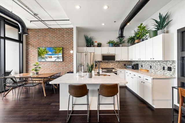 175 S 2nd St S Ph-16, Saint Petersburg, FL 33701 - kitchen with stainless steel appliances, a sink, white cabinetry, a center island with sink, and backsplash