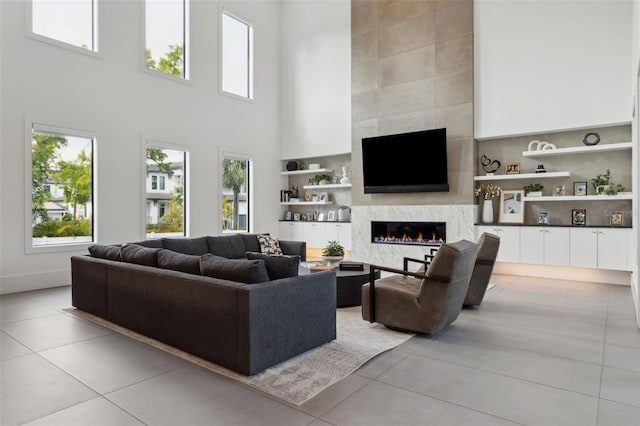 2902 S Beach Dr, Tampa, FL 33629 - living area featuring tile patterned flooring, a high end fireplace, a towering ceiling, built in shelves, and baseboards