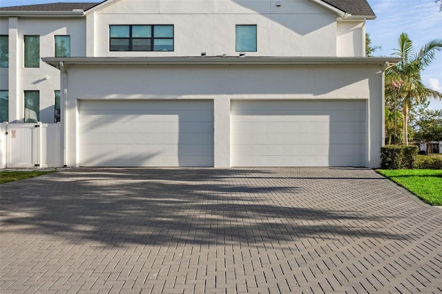 2902 S Beach Dr, Tampa, FL 33629 - view of property exterior featuring decorative driveway, an attached garage, stucco siding, and fence