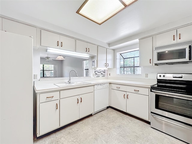 1556 Lynda Ln, Dunedin, FL 34698 - kitchen with white appliances, a sink, light countertops, and plenty of natural light
