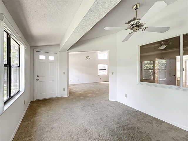 1556 Lynda Ln, Dunedin, FL 34698 - carpeted spare room featuring a textured ceiling, a ceiling fan, healthy amount of natural light, lofted ceiling, and baseboards