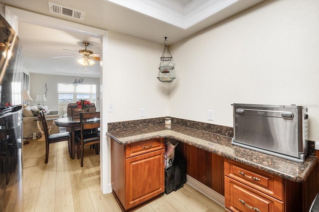 5130 Brittany Dr S Unit 604, Saint Petersburg, FL 33715 - kitchen featuring a ceiling fan, light wood-style floors, brown cabinets, dark stone counters, and open floor plan