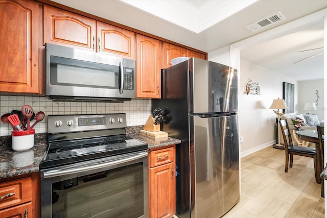 5130 Brittany Dr S Unit 604, Saint Petersburg, FL 33715 - kitchen featuring stainless steel appliances, backsplash, brown cabinetry, light wood-style flooring, and baseboards