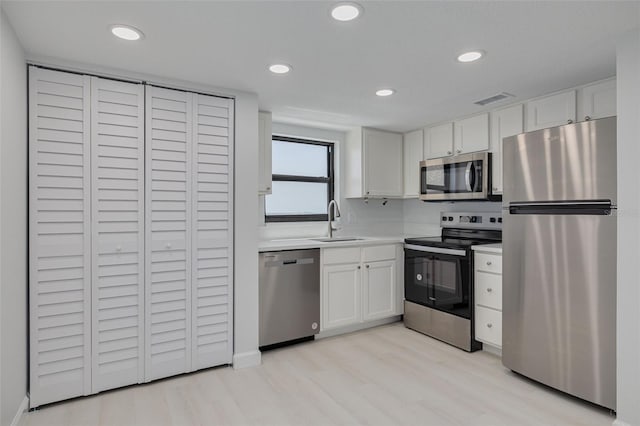 7050 Sunset Dr S Unit 1401, South Pasadena, FL 33707 - kitchen with appliances with stainless steel finishes, a sink, white cabinetry, light countertops, and light wood-style flooring