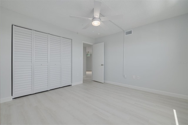 7050 Sunset Dr S Unit 1401, South Pasadena, FL 33707 - unfurnished bedroom with wood finished floors, a closet, baseboards, ceiling fan, and a textured ceiling