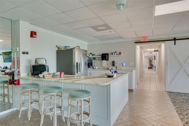 7050 Sunset Dr S Unit 1401, South Pasadena, FL 33707 - kitchen featuring stainless steel refrigerator with ice dispenser, white cabinetry, a kitchen breakfast bar, ornamental molding, and a peninsula