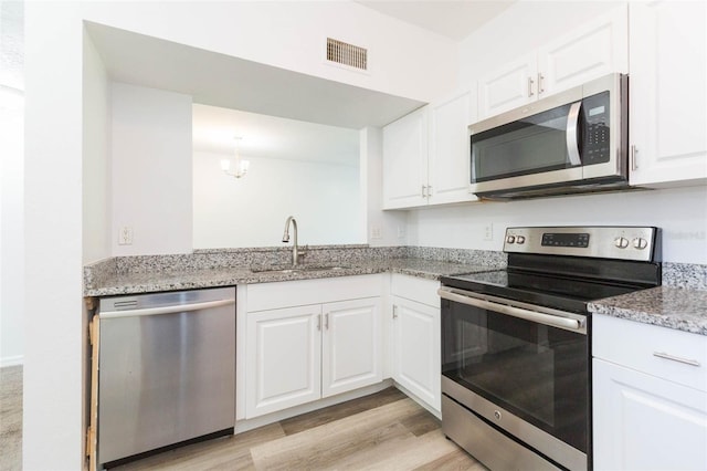 9524 Newdale Way Unit 101, Riverview, FL 33578 - kitchen with stainless steel appliances, a sink, white cabinets, light wood-style flooring, and a chandelier