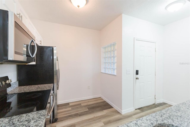 9524 Newdale Way Unit 101, Riverview, FL 33578 - kitchen featuring stainless steel appliances, light wood-style floors, white cabinetry, light stone counters, and baseboards