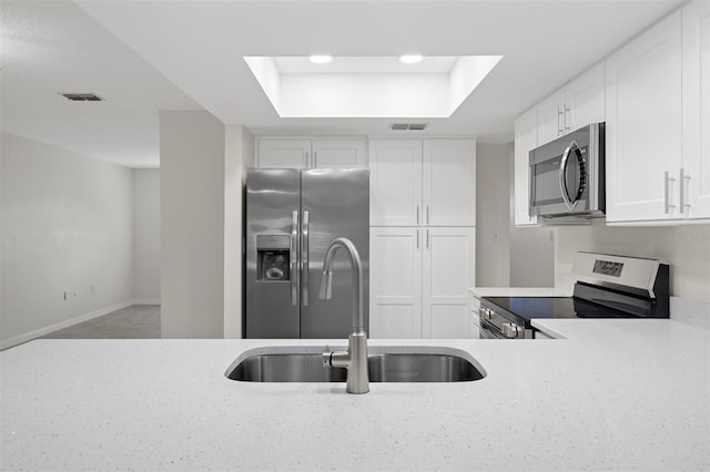 4315 Flexer Dr, Hernando Beach, FL 34607 - kitchen with stainless steel appliances, a sink, a raised ceiling, light stone counters, and white cabinets