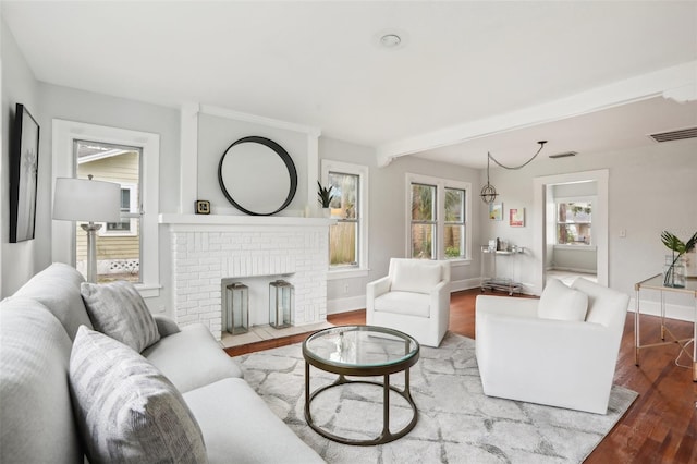 2015 3rd St S, Saint Petersburg, FL 33705 - living area with wood finished floors, baseboards, beam ceiling, and a brick fireplace