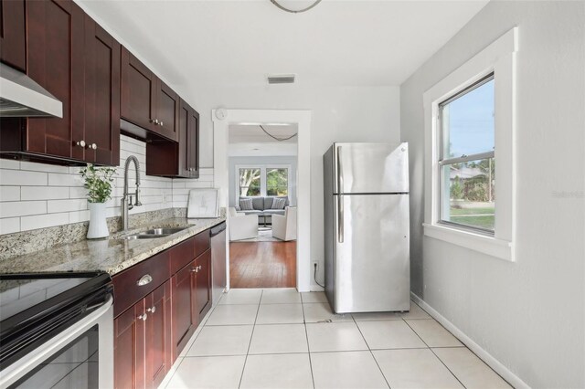 2015 3rd St S, Saint Petersburg, FL 33705 - kitchen featuring stainless steel appliances, a sink, light stone counters, decorative backsplash, and baseboards