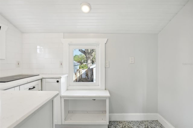 2015 3rd St S, Saint Petersburg, FL 33705 - kitchen featuring white cabinets, baseboards, light countertops, and black electric cooktop