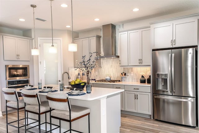 13722 Heartwood Way, Parrish, FL 34219 - kitchen featuring stainless steel appliances, wall chimney exhaust hood, light countertops, light wood-style flooring, and a sink