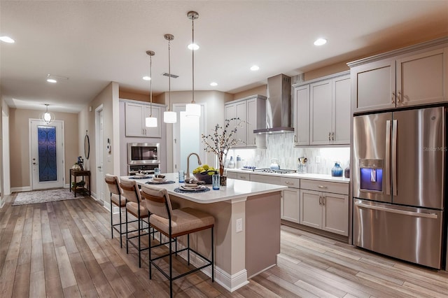 13722 Heartwood Way, Parrish, FL 34219 - kitchen with stainless steel appliances, wall chimney exhaust hood, light wood-type flooring, light countertops, and a kitchen breakfast bar