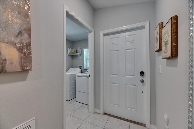 foyer entrance with washer and clothes dryer, light tile patterned floors, and baseboards