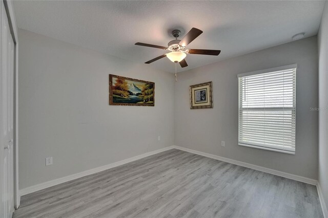 spare room with light wood-style floors, ceiling fan, a smoke detector, and baseboards