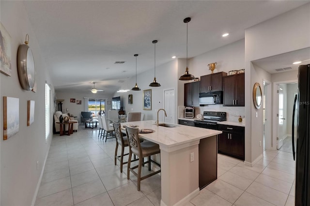 kitchen featuring black appliances, a sink, light tile patterned flooring, a kitchen breakfast bar, and recessed lighting