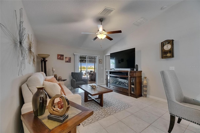 living area with ceiling fan, lofted ceiling, light tile patterned floors, and baseboards