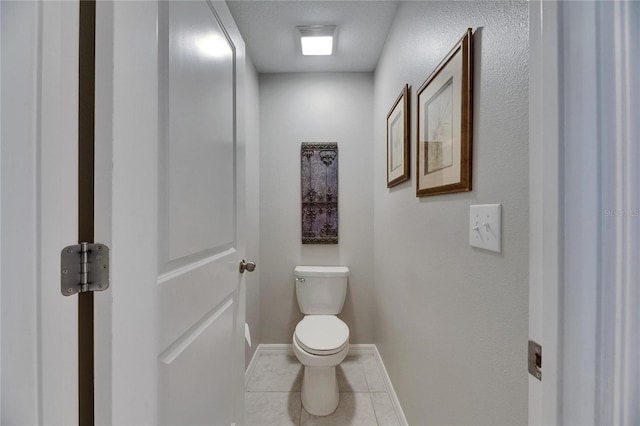 bathroom with toilet, tile patterned floors, and baseboards