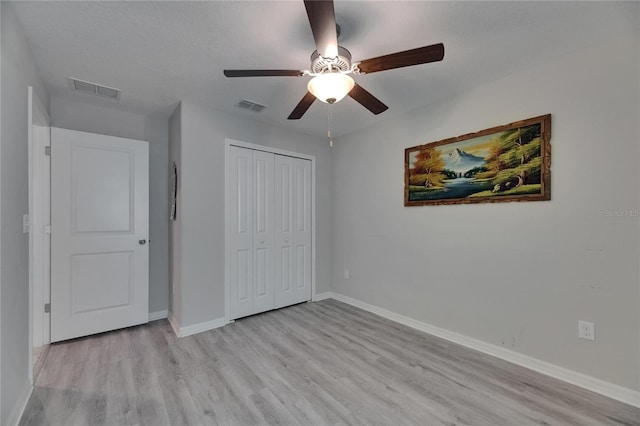 unfurnished bedroom with light wood-type flooring, baseboards, a closet, and ceiling fan