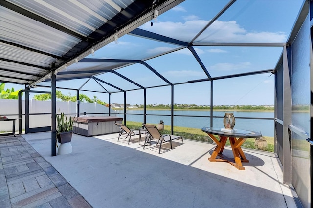 view of patio / terrace with a hot tub, a water view, a lanai, and fence