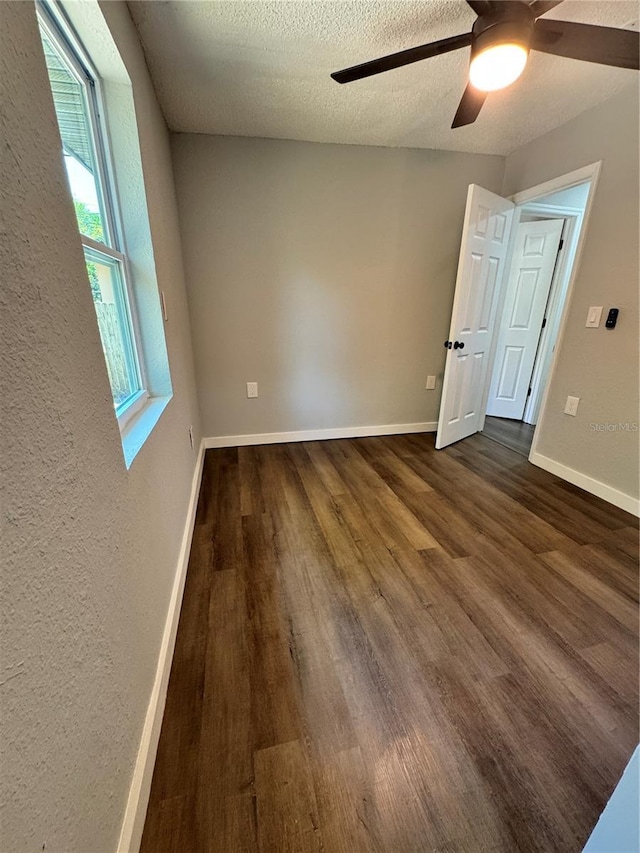 1675 13th Ave S, Saint Petersburg, FL 33712 - empty room with dark wood-style flooring, ceiling fan, baseboards, a textured ceiling, and a textured wall