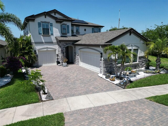 13103 Monach Isles Dr, Riverview, FL 33579 - view of front facade with stucco siding, roof mounted solar panels, decorative driveway, and stone siding