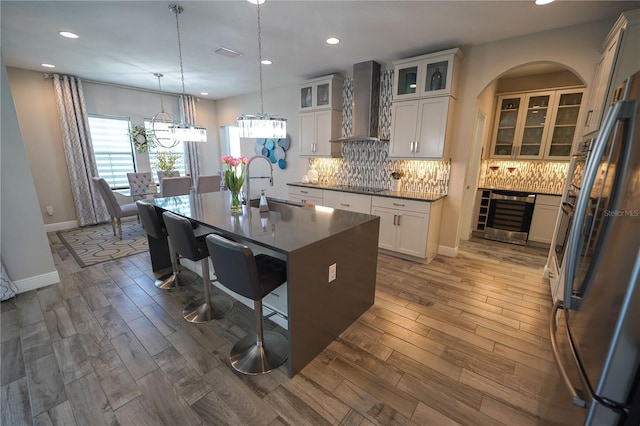 13103 Monach Isles Dr, Riverview, FL 33579 - kitchen with wall chimney range hood, a sink, black electric cooktop, decorative backsplash, and wine cooler