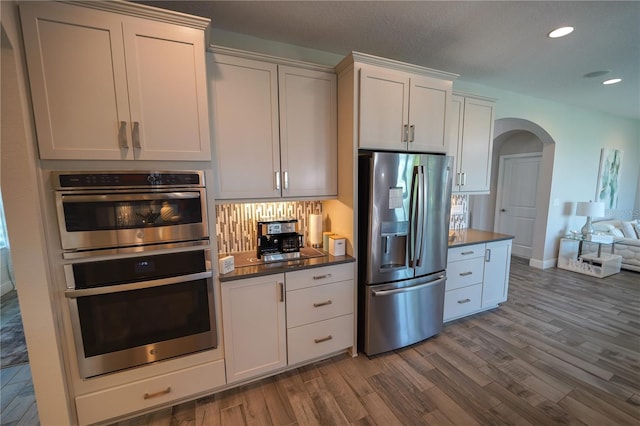 13103 Monach Isles Dr, Riverview, FL 33579 - kitchen with stainless steel appliances, arched walkways, recessed lighting, dark wood-type flooring, and dark countertops