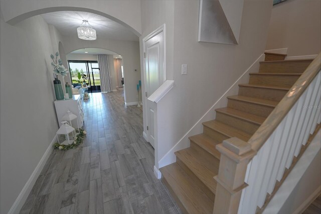 13103 Monach Isles Dr, Riverview, FL 33579 - hallway featuring arched walkways, baseboards, stairs, and wood finished floors