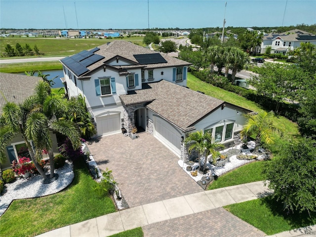 13103 Monach Isles Dr, Riverview, FL 33579 - view of front of home with roof with shingles, decorative driveway, stucco siding, roof mounted solar panels, and an attached garage