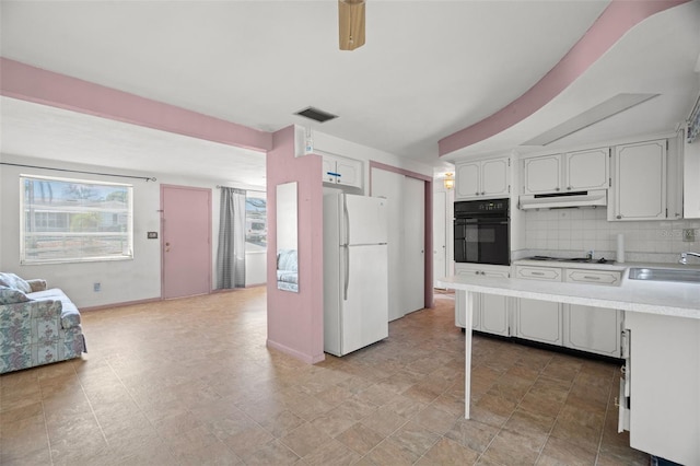 3348 Clydesdale Dr, Holiday, FL 34691 - kitchen featuring freestanding refrigerator, black oven, under cabinet range hood, light countertops, and decorative backsplash