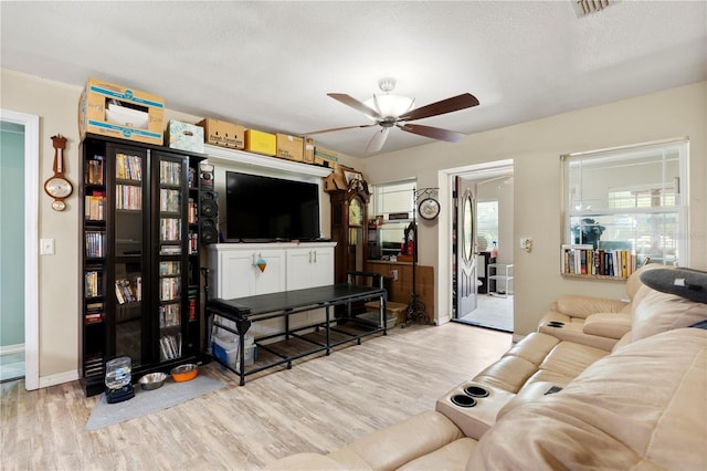 living room with wood finished floors, a ceiling fan, and baseboards