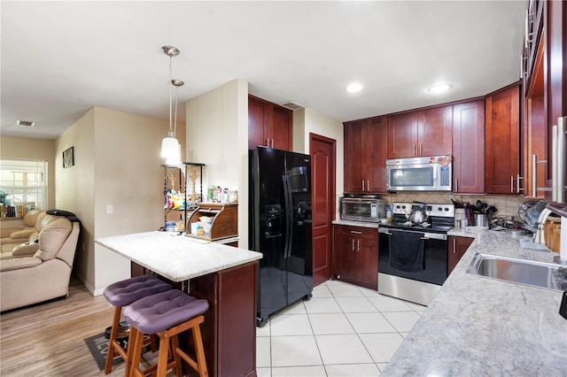 kitchen with appliances with stainless steel finishes, reddish brown cabinets, a sink, light countertops, and recessed lighting