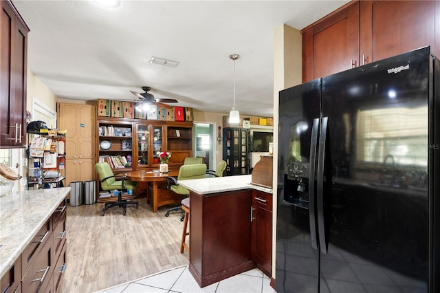 kitchen featuring black fridge with ice dispenser, ceiling fan, a desk, a peninsula, and light stone countertops