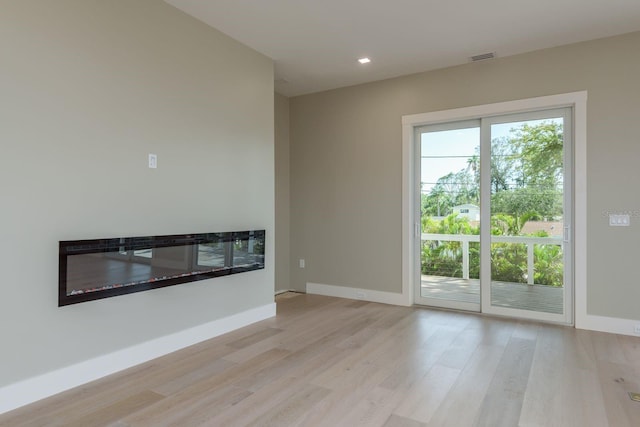 3752 Arkansas Ave NE, Saint Petersburg, FL 33703 - unfurnished living room with light wood-style flooring, baseboards, a glass covered fireplace, and recessed lighting