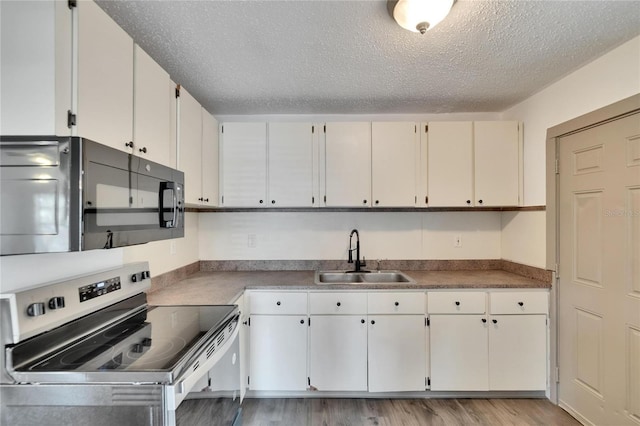 1920 E Chelsea St, Tampa, FL 33610 - kitchen with stainless steel electric range oven, black microwave, a sink, a textured ceiling, and light wood-style floors