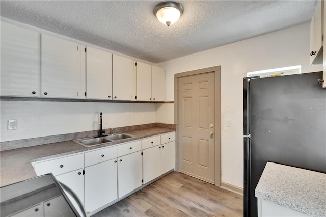 1920 E Chelsea St, Tampa, FL 33610 - kitchen featuring freestanding refrigerator, a sink, light wood-type flooring, a textured ceiling, and white cabinets