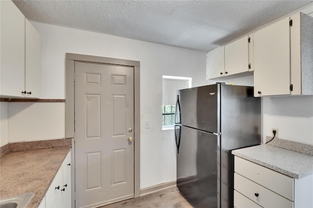 1920 E Chelsea St, Tampa, FL 33610 - kitchen featuring freestanding refrigerator, light wood-style flooring, light countertops, white cabinets, and a textured ceiling