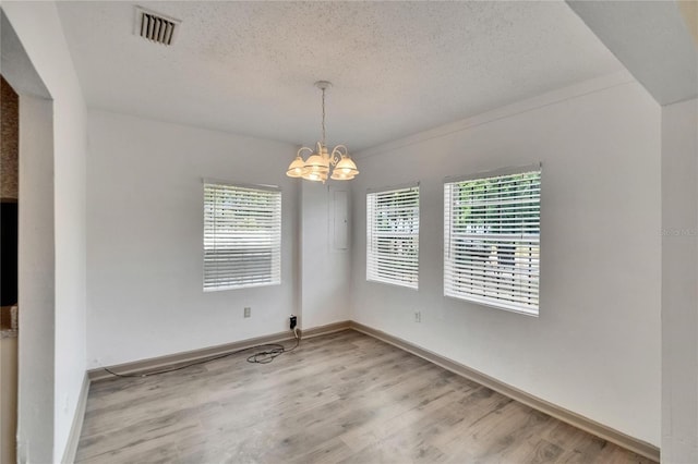 1920 E Chelsea St, Tampa, FL 33610 - spare room featuring a chandelier, light wood-style flooring, a textured ceiling, and plenty of natural light