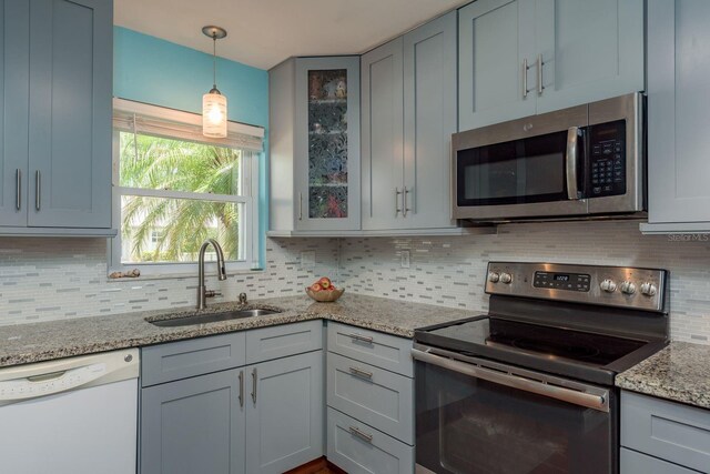 1065 Tartan Dr Unit C, Palm Harbor, FL 34684 - kitchen with appliances with stainless steel finishes, a sink, tasteful backsplash, glass insert cabinets, and decorative light fixtures