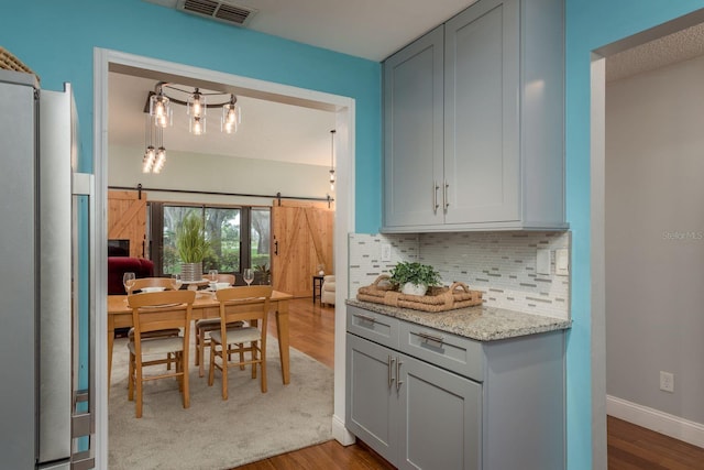 1065 Tartan Dr Unit C, Palm Harbor, FL 34684 - kitchen with refrigerator, a barn door, decorative backsplash, and wood finished floors