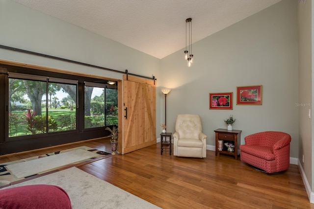 1065 Tartan Dr Unit C, Palm Harbor, FL 34684 - living area featuring vaulted ceiling, wood finished floors, a barn door, baseboards, and a textured ceiling