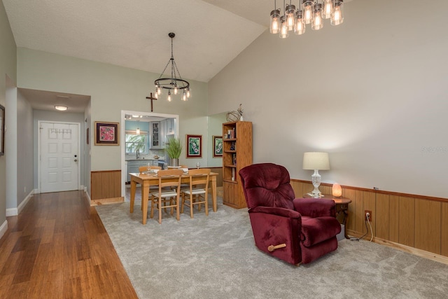 1065 Tartan Dr Unit C, Palm Harbor, FL 34684 - dining space with a chandelier, wood finished floors, wainscoting, high vaulted ceiling, and wooden walls