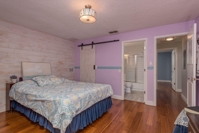 1065 Tartan Dr Unit C, Palm Harbor, FL 34684 - bedroom featuring wood finished floors, a textured ceiling, a barn door, wood walls, and baseboards