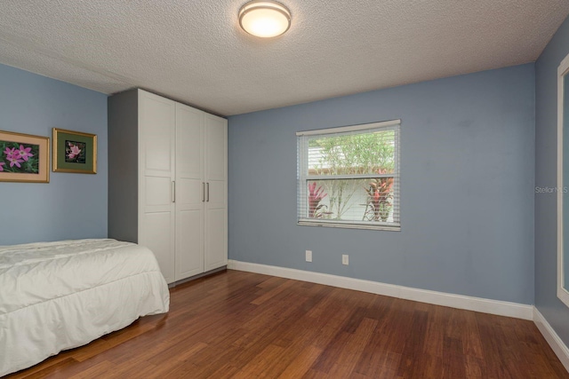 1065 Tartan Dr Unit C, Palm Harbor, FL 34684 - bedroom featuring dark wood-style flooring, baseboards, a textured ceiling, and a closet