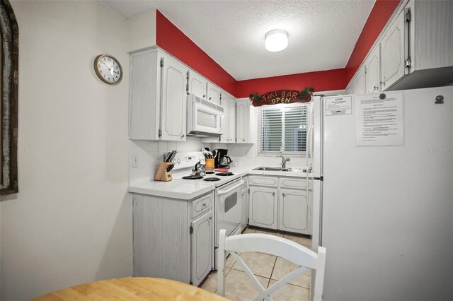 600 71st Ave Unit 18, St Pete Beach, FL 33706 - kitchen with white appliances, a sink, light countertops, a textured ceiling, and light tile patterned flooring