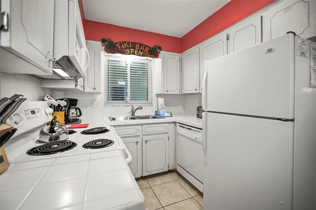600 71st Ave Unit 18, St Pete Beach, FL 33706 - kitchen featuring white appliances, a sink, tile counters, white cabinets, and decorative backsplash